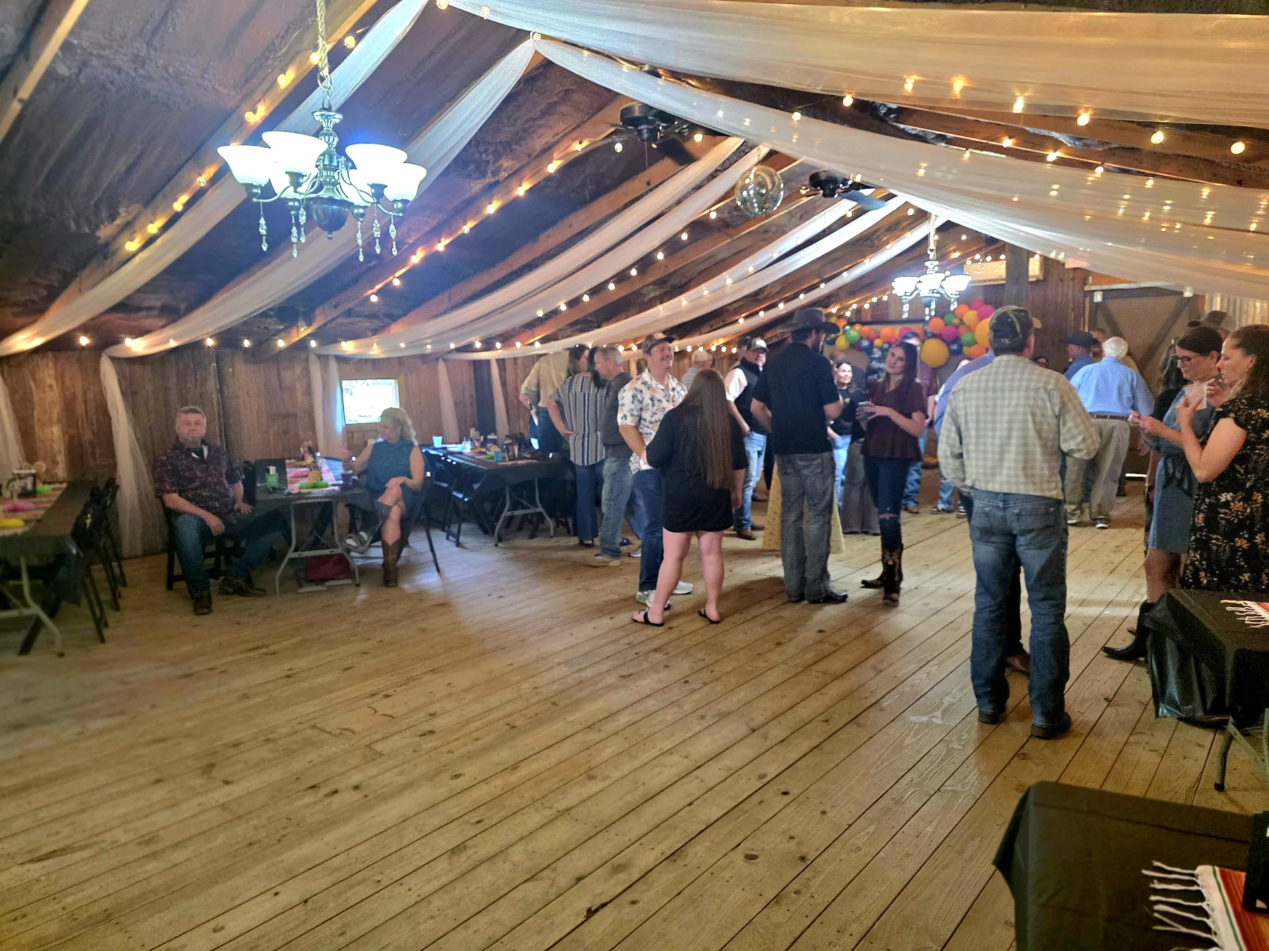 Guests celebrating inside the reception barn at Chisholm Trail Rustic Venue