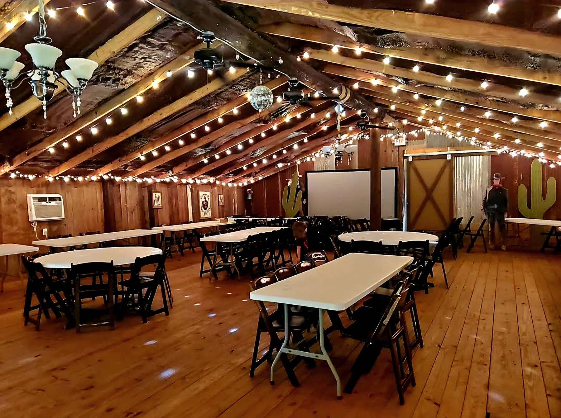 Reception barn with string lights and tables at Chisholm Trail Rustic Venue