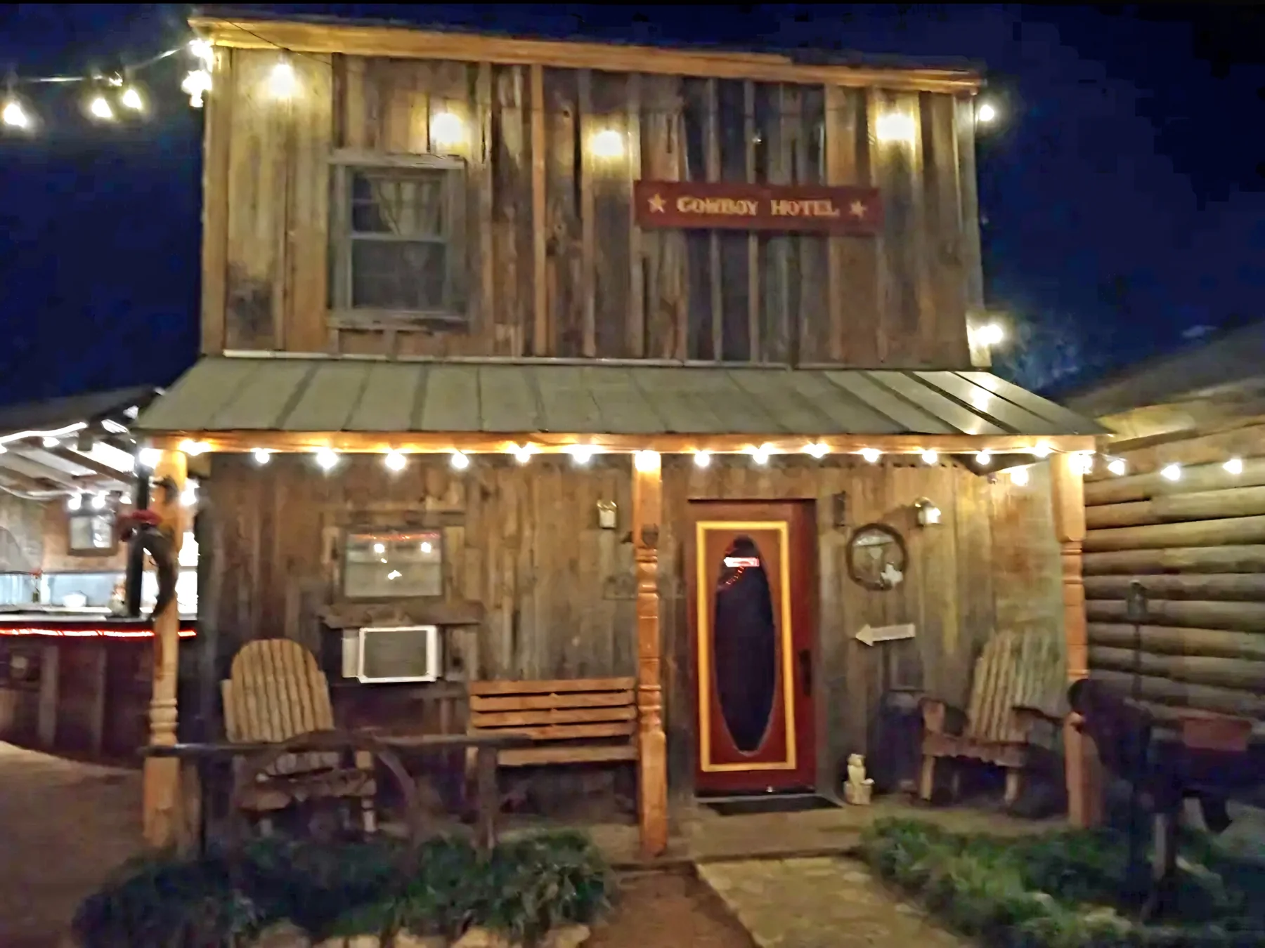 Western hotel storefront lit at night at Chisholm Trail Rustic Venue